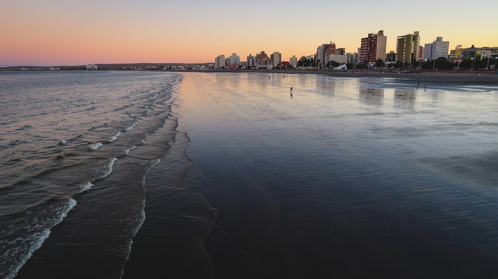 Puerto Madryn Patagonia coastline at sunset with tidal flats and reflections along Golfo Nuevo Argentina Sunset over the tidal flats of Puerto Madryn Patagonia Argentina with calm Atlantic waters and city skyline reflecting across the shoreline of Golfo Nuevo along the windswept Patagonian coast.