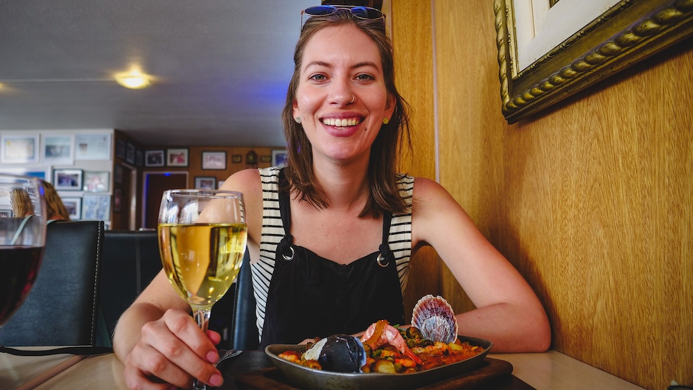 Audrey Bergner enjoying Patagonian seafood and wine in Puerto Madryn Argentina Puerto Madryn seafood restaurant in Atlantic Patagonia Argentina where Audrey Bergner enjoys a plate of fresh Patagonian seafood with white wine highlighting the coastal cuisine shaped by the rich marine ecosystem of Chubut.