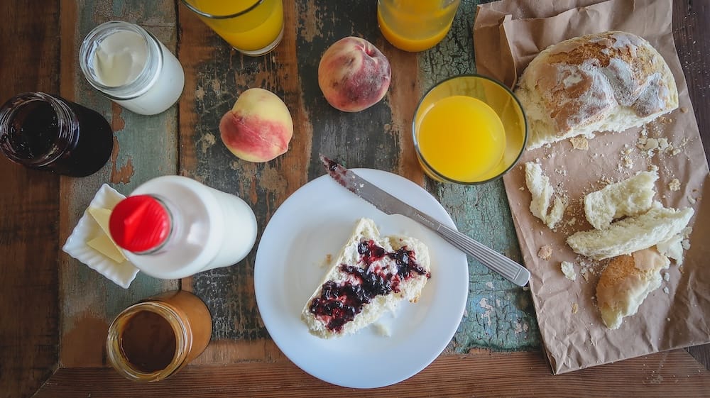 Argentine breakfast in Puerto Pirámides, Chubut, Patagonia, Argentina, with fresh bread, peaches, orange juice, milk, yogurt and sweet spreads arranged on a rustic wooden table.