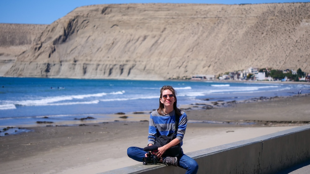 Rada Tilly beach and coastal cliffs in Chubut Patagonia with Audrey Bergner Rada Tilly beach and towering coastal cliffs in Chubut Patagonia Argentina where Audrey Bergner sits along the seaside promenade overlooking the wide sandy shoreline and calm Atlantic waters of this elegant Patagonian resort town.