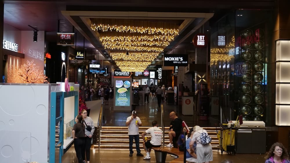 Restaurant and Entertainment Corridor at West Edmonton Mall in Edmonton Busy restaurant and entertainment corridor inside West Edmonton Mall in Edmonton, Alberta, with Moxies Grill & Bar, Five & Dive, 1st RND and other dining venues beneath decorative ceiling lights.