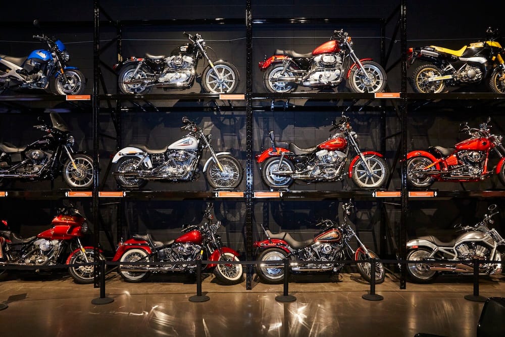 Rows of motorcycles are displayed on multi-level racks inside the Reynolds Museum in Wetaskiwin, Alberta, Canada, showing different styles, eras and colours under gallery lighting.
