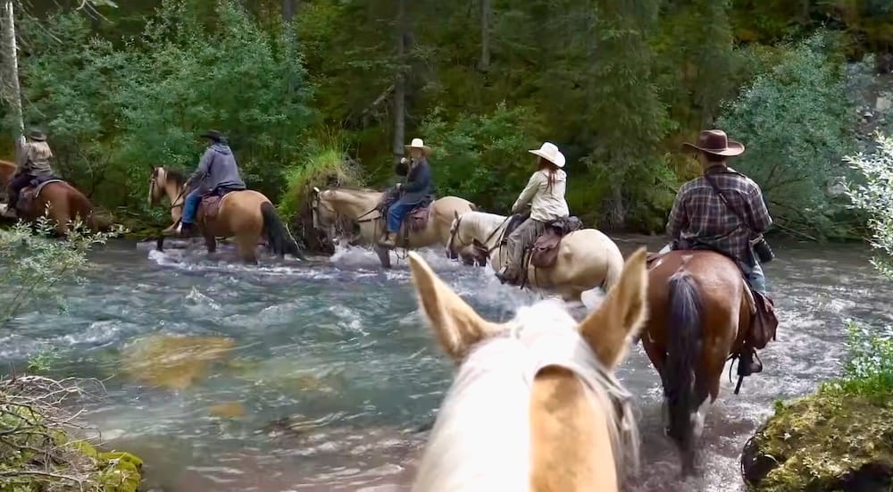 Cruce de río en grupo, Banff Trail Riders, Parque Nacional Banff, Alberta, Canadá Un grupo de jinetes a caballo cruza juntos un río caudaloso durante una excursión a caballo por el interior con Banff Trail Riders en el Parque Nacional Banff, Alberta, Canadá.