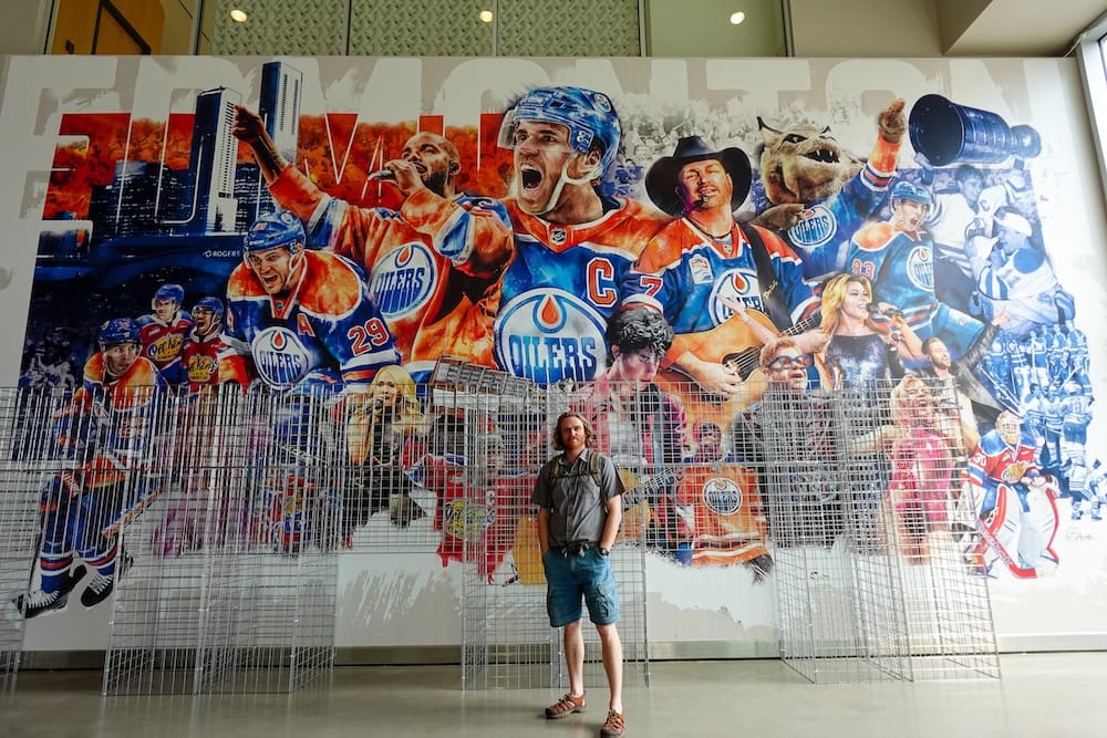 Edmonton Oilers mural inside Rogers Place in Edmonton, Alberta, Canada, with Samuel Jeffery Samuel Jeffery stands in front of a large Edmonton Oilers mural featuring players, musicians and team imagery inside Rogers Place in Edmonton, Alberta, Canada.