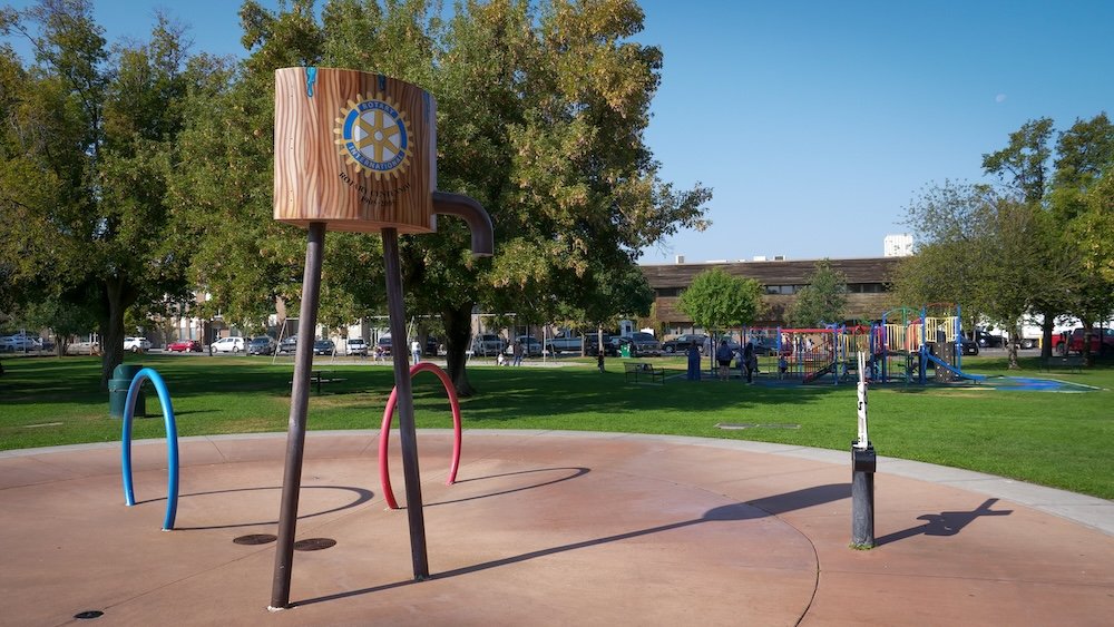 Family-friendly playground and splash pad at Rotary Park in Cranbrook, BC Rotary Park in Cranbrook, BC featuring a colorful playground and splash pad area surrounded by open green space, showing why this centrally located park is a favorite family-friendly spot for parents visiting with babies or toddlers who need an easy outdoor break.