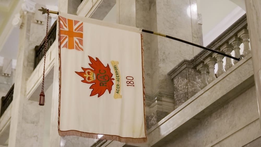 Historic Military Banner Inside the Royal Alberta Museum in Edmonton, Alberta, Canada Historic military banner suspended inside the Royal Alberta Museum in Edmonton, Alberta, Canada, framed by pale marble columns, stair railings and the museum’s grand interior architecture.
