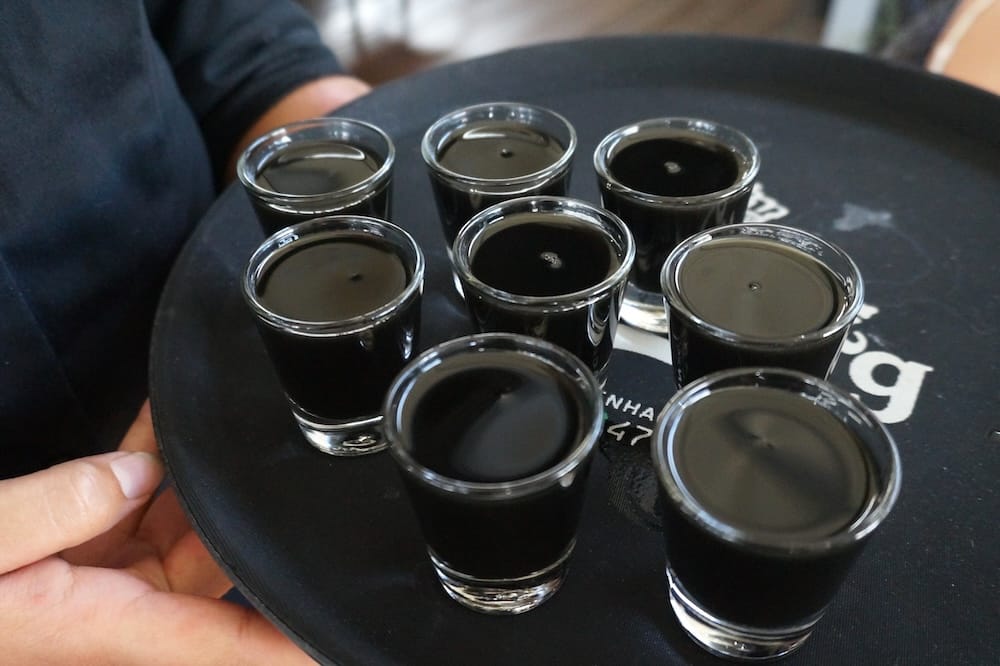 Eight dark salmiakki shots served in small glasses on a black tray during our Finnish archipelago visit, showing the alcoholic liqueur version of Finland’s famously salty licorice flavour.
