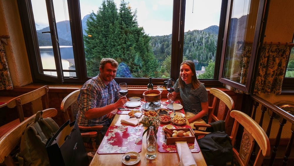 Samuel Jeffery and Audrey Bergner, fondue dinner, Restaurante Patagonia, Llao Llao Hotel, Bariloche, Río Negro, Argentina Samuel Jeffery and Audrey Bergner raising wine glasses at a window table set with a fondue pot, overlooking Nahuel Huapi Lake and forested hills from Restaurante Patagonia at Llao Llao Hotel near Bariloche, Río Negro, Argentina.