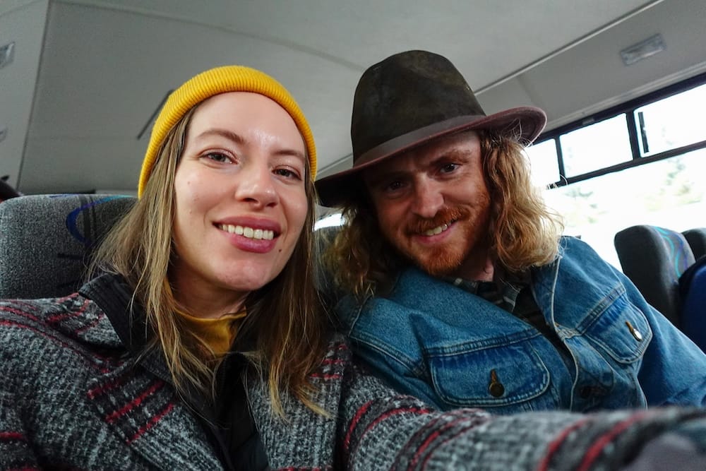 Samuel Jeffery and Audrey Bergner smile for a selfie seated inside a guided tour shuttle bus, on a day trip in Banff National Park, Alberta, Canada.