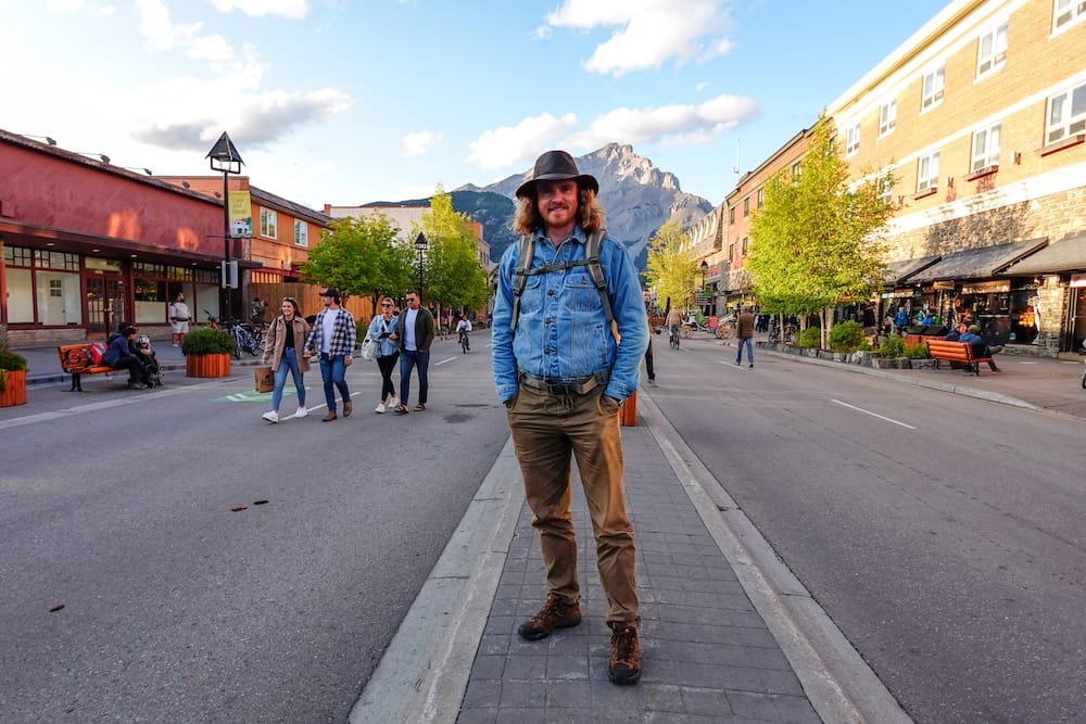 Samuel Jeffery on Banff Avenue, downtown Banff townsite, Banff National Park, Alberta Samuel Jeffery stands on Banff Avenue in downtown Banff, with pedestrians, cyclists, storefronts, and Cascade Mountain rising at the end of the street, Banff National Park, Alberta, Canada.