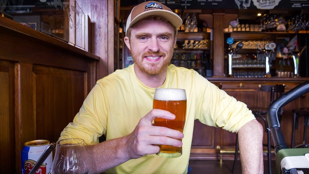 Samuel Jeffery Enjoying Craft Beer at a Wooden Bar in San Carlos de Bariloche, Argentina Samuel Jeffery smiles while holding a glass of craft beer inside a warm wooden bar in San Carlos de Bariloche, a practical starting point for exploring northern Patagonia.