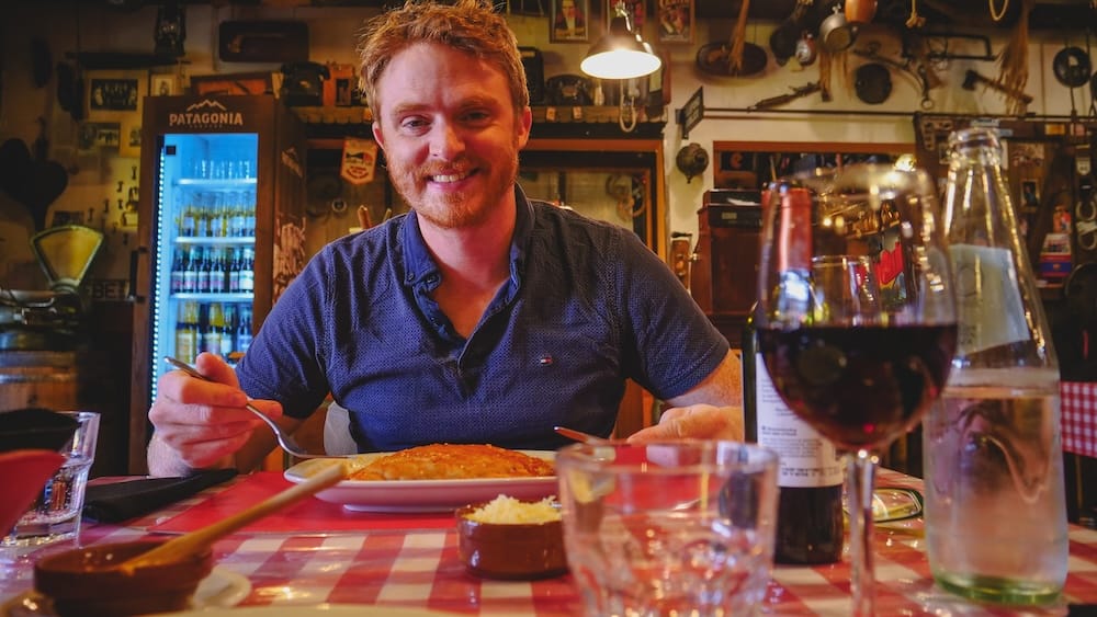 Samuel Jeffery Almorzando Pasta en Esquel Patagonia Argentina Esquel restaurantes: Samuel Jeffery come un plato de pasta en Chubut, donde los locales cobran cargos separados por la salsa.