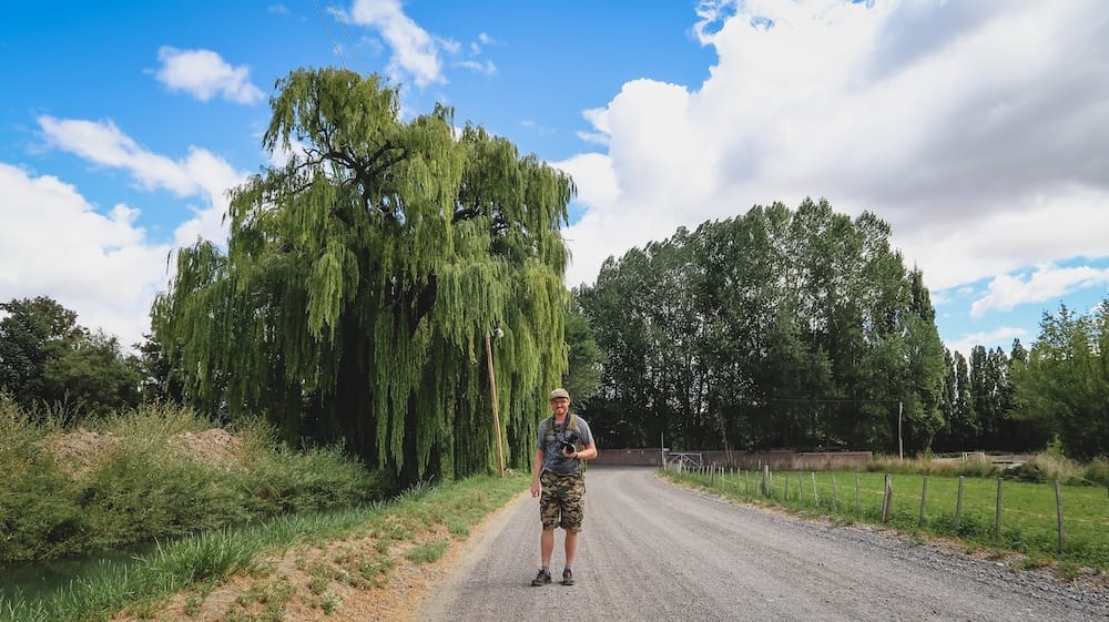 Samuel Jeffery parado en un camino de ripio bajo un sauce llorón en Gaiman Patagonia Argentina, mostrando la tranquilidad rural del pueblo