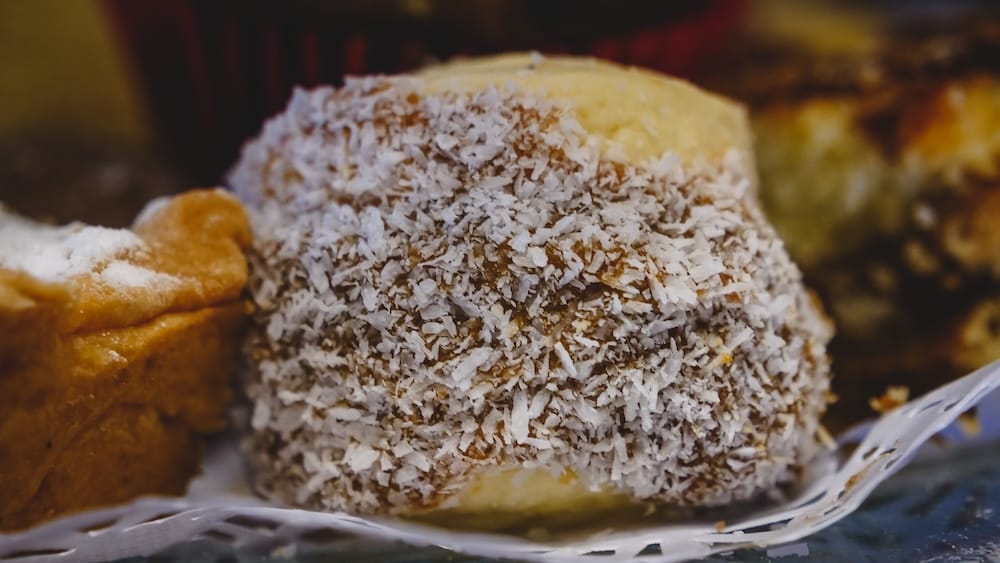 An insanely thick alfajor filled with dulce de leche and coated in coconut at a café in San Martin de los Andes, Argentina, highlighting Patagonia’s rich merienda tradition and indulgent high-calorie dessert culture.
