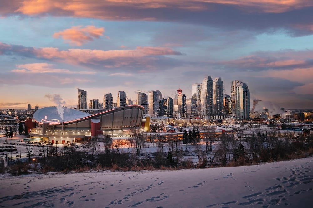 A winter dusk view from Scotsman's Hill overlooking the illuminated Scotiabank Saddledome and downtown Calgary's snow-dusted skyline, Alberta, Canada.