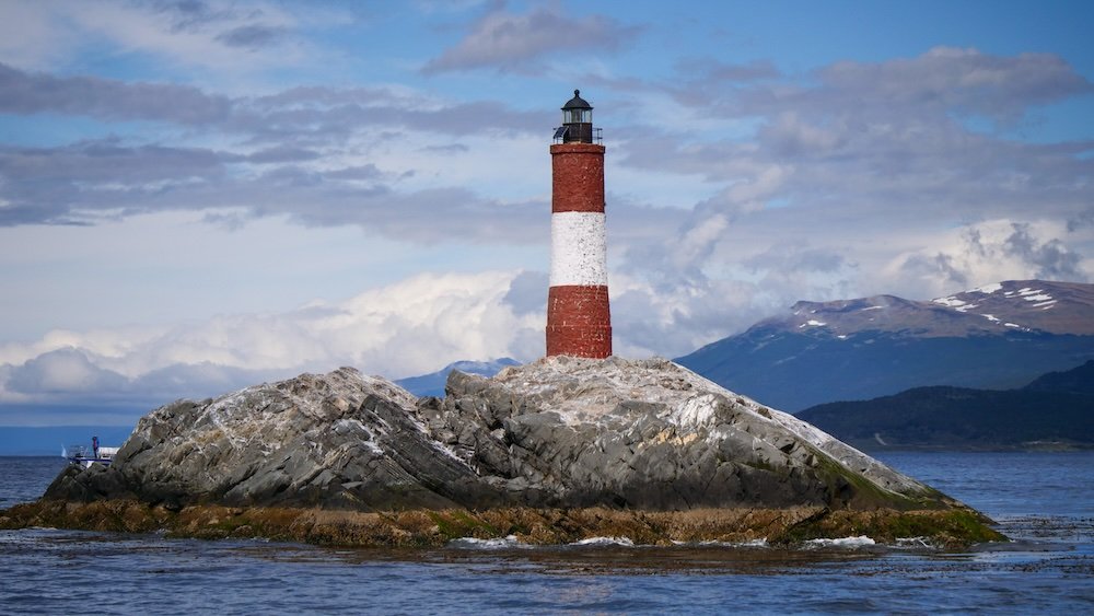 See the Lighthouse and End of the World in its red and white glory while on boat tour in Ushuaia, Argentina