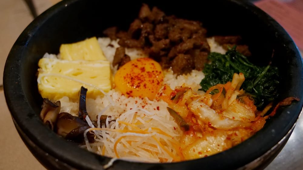Dolsot bibimbap en bol de piedra caliente en Shoku Izakaya, Banff, Alberta, Canadá Dolsot bibimbap en Shoku Izakaya, Banff, Alberta, Canadá, servido en un bol negro de piedra con arroz, yema de huevo, carne, kimchi, hojas verdes, hongos, verduras ralladas y huevo en tiras.