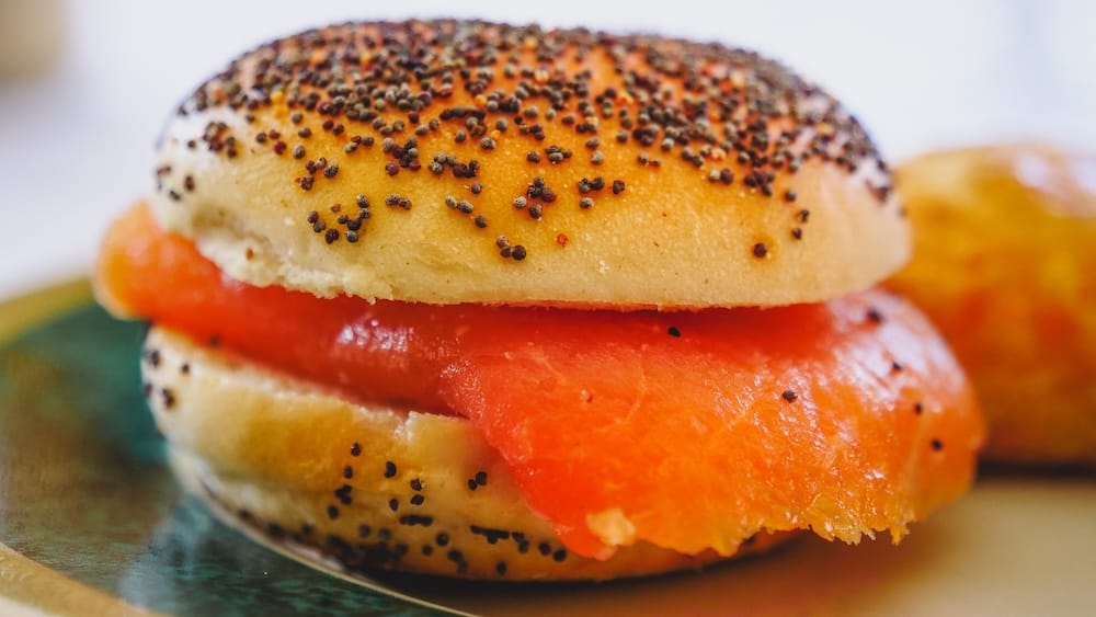Smoked Salmon and Cream Cheese Poppy Seed Bagel at Llao Llao Hotel Afternoon Tea A close-up of a mini poppy seed bagel filled with cream cheese and smoked salmon, served as part of the savory course during afternoon tea at Llao Llao Hotel in Bariloche, Río Negro, Argentine Patagonia, Argentina.