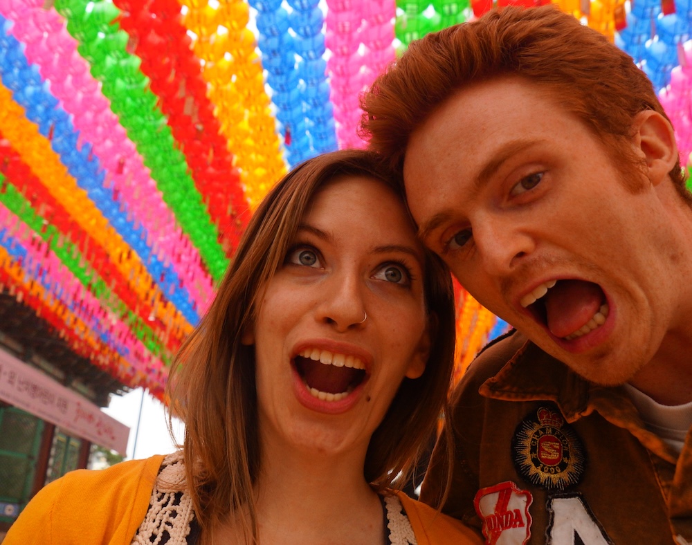 South Korea English-teaching days, with young Nomadic Samuel and Audrey Bergner taking a playful selfie under colorful hanging lanterns, capturing the moment they first met while teaching abroad.