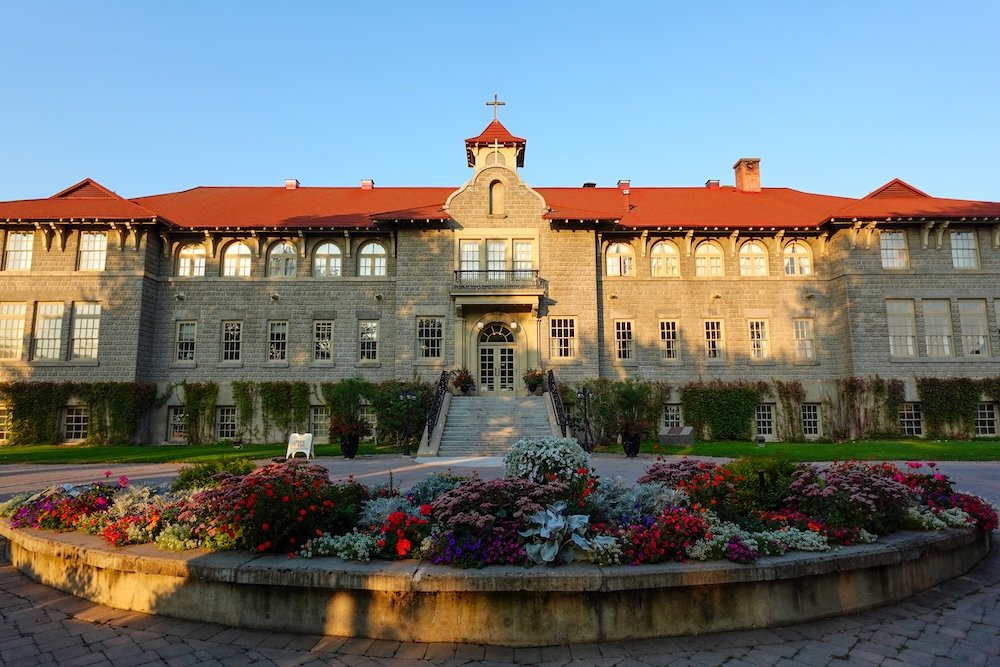 St. Eugene Mission near Cranbrook, British Columbia: historic stone mission building and gardens photographed in warm evening light, a significant cultural site and former residential school now operating as a resort and interpretive destination.