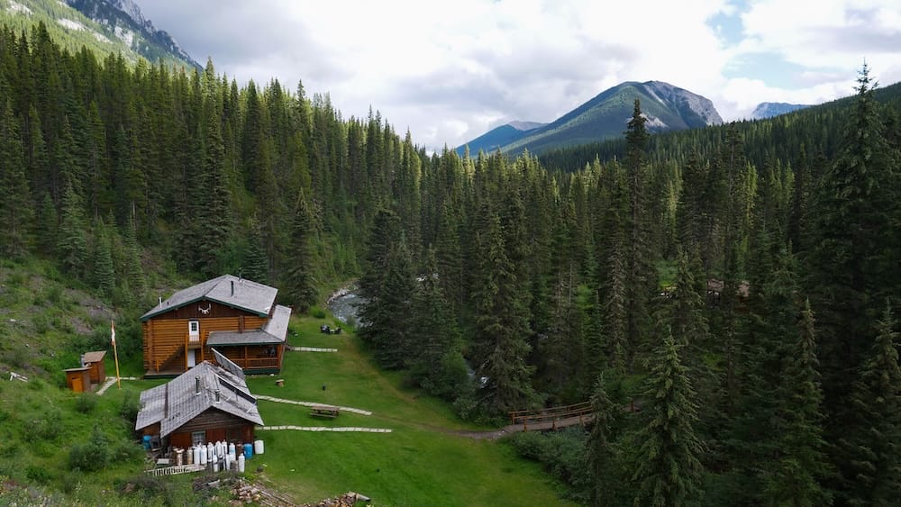 Sundance Lodge in Banff National Park, Alberta, Canada surrounded by forest and mountains on the six-day horseback trip Sundance Lodge sits in a forested clearing in Banff National Park, Alberta, Canada, surrounded by dense evergreen trees, a creek and layered mountain slopes rising behind the backcountry property.