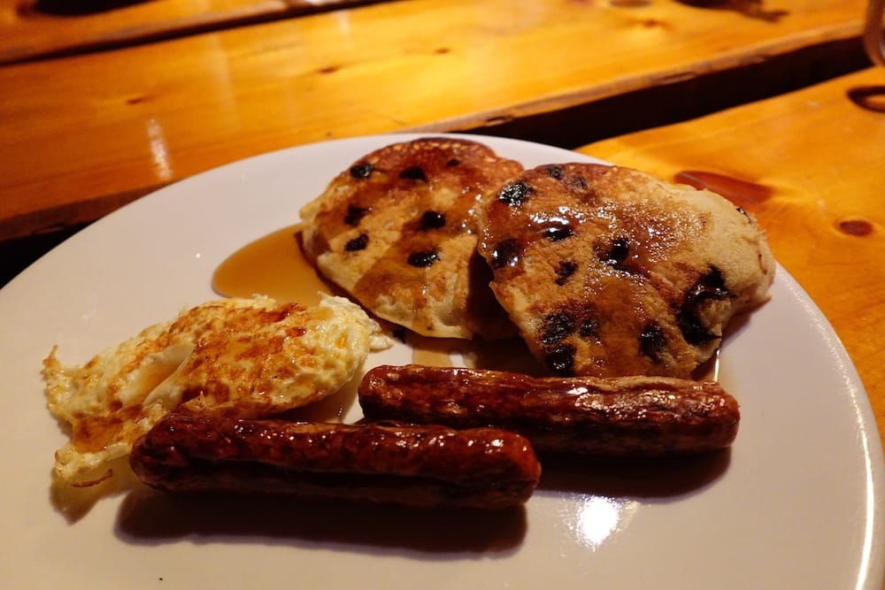 Un desayuno abundante de pancakes con almíbar, huevos fritos y salchichas servido en Sundance Lodge, Parque Nacional Banff, Alberta, Canadá, durante una travesía a caballo de Banff Trail Riders.