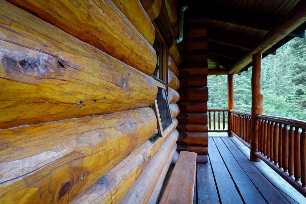 Galería de Sundance Lodge en el Parque Nacional Banff, Alberta, Canadá, con construcción de troncos y vistas al bosque del backcountry Galería de madera a lo largo del exterior de Sundance Lodge, en el Parque Nacional Banff, Alberta, Canadá, con gruesas paredes de troncos, barandas rústicas y bosque de coníferas visible más allá de la veranda.