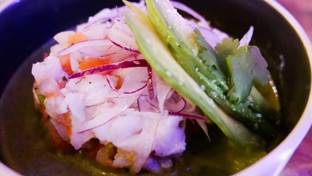 Primer Plano del Ceviche de Pescado Mexicano en Taco Shop, Bourbon Street, West Edmonton Mall, Alberta, Canadá Primer plano de ceviche de pescado mexicano con palta en láminas, cebolla morada encurtida y cilantro en caldo cítrico, servido en un bowl negro en Taco Shop, Bourbon Street, West Edmonton Mall, Alberta, Canadá.