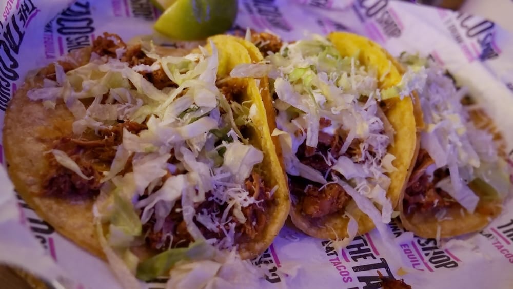 Chicken Tinga Tacos at The Taco Shop in West Edmonton Mall, Edmonton, Alberta, Canada Close-up of three chicken tinga tacos at The Taco Shop in West Edmonton Mall, Edmonton, Alberta, Canada, topped with shredded lettuce, grated cheese and served with lime.