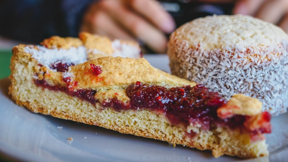 Tartaleta de Membrillo and Alfajor Patagonia Quince Tart and Coconut Cookie Dessert Tartaleta de membrillo quince tart alongside a coconut-covered alfajor in Patagonia, highlighting dense pastry construction and preserved fruit fillings designed for shelf stability and practical fuel in Argentina’s southern bakery culture.