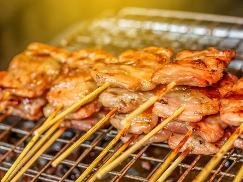 Premium Photo  Closeup of grilled skewered milk pork on stick thai street  food market