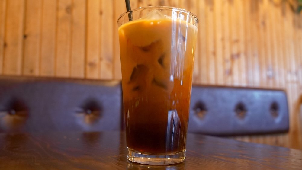 Thai iced tea served at Family Thai Restaurant in Cranbrook, British Columbia, shown in a tall glass with ice and creamy orange tea, enjoyed as a refreshing drink to cool down after eating a spicy green coconut curry during our dinner visit.