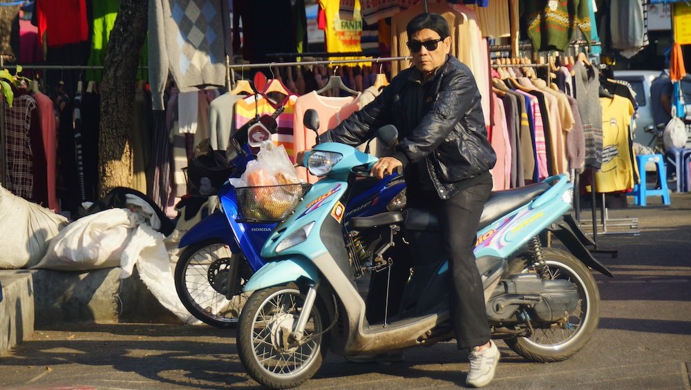 Thai man wearing a leather jacket and sunglasses on a motorcycle in Chiang Mai, Thailand 