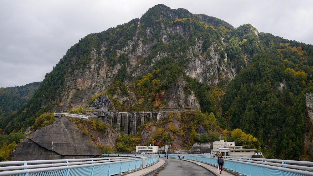 That Backpacker Audrey Bergner as a small speck crossing the Kurobe Dam on Foot Tallest Dam in Japan 186 Meters