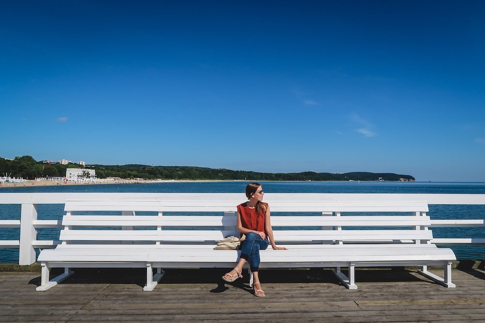 That Backpacker Audrey Bergner enjoying a quiet moment sitting down on a bench on the pier in Sopot, Poland 