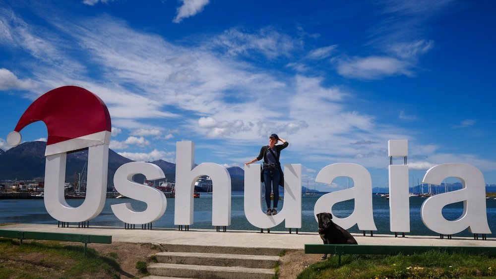 That Backpacker Audrey Bergner posing by the Ushuaia sign in Tierra del Fuego, Argentina 