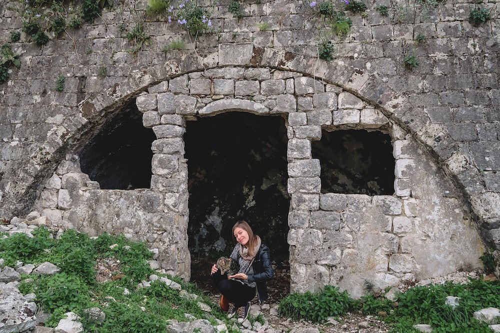 That Backpacker Audrey Bergner posing with a cat nearby Church of Our Lady of Remedy Crkva Gospe od Zdravlja aka Crkva Marije Koleđate in Kotor, Montenegro