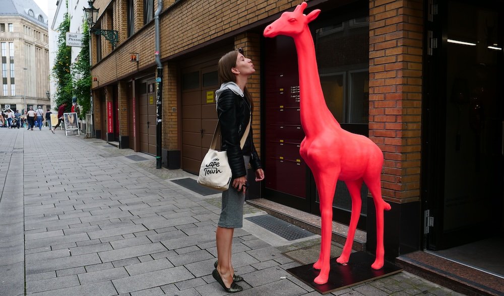 That Backpacker Audrey Bergner standing next to a red plastic giraffe in Dusseldorf, Germany 