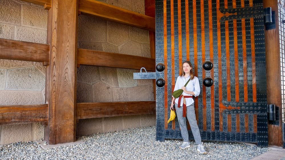 That Backpacker Audrey Bergner standing outside of a large gateway door at Kanazawa Castle Park 