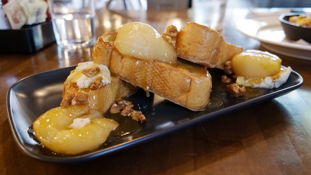Close-up of French toast at The Beltliner in Calgary, Alberta, Canada, served with syrup, creamy topping and nuts on a black plate during the sweet side of our Calgary brunch.