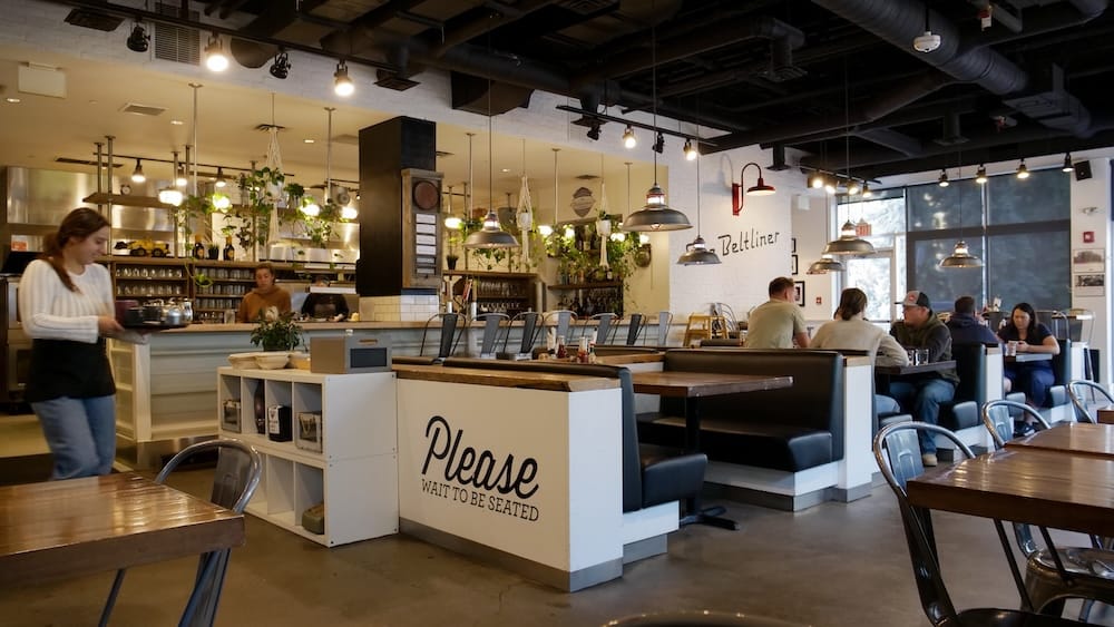 The Beltliner Diner Interior, Beltline Neighbourhood, Calgary, Alberta, Canada Interior of The Beltliner diner in Calgary with an industrial-style pendant-lit dining room, wait staff, and a "Please Wait to Be Seated" host stand near the entrance.