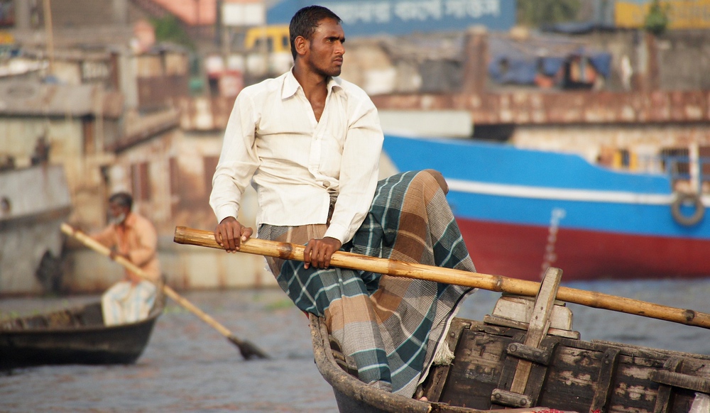 The button down shit and lungi (Bangladeshi skirt for men) are typical attire for Bangladeshi men – especially the oarsmen.
