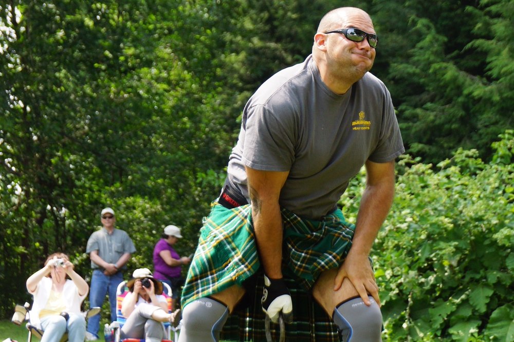 The facial expression of a man mustering up strength to throw a weight over his head at the New Brunswick Highland Games