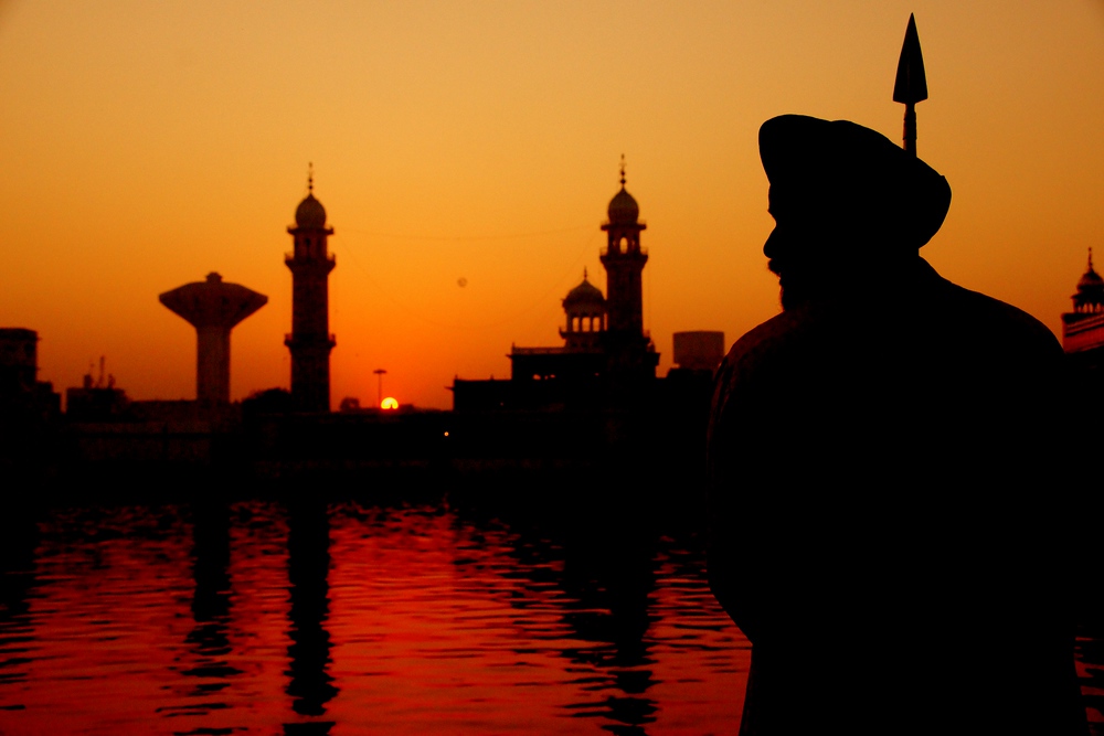 This guard is rendered as a silhouette during sunrise at the Golden Temple in Amritsar, Punjab