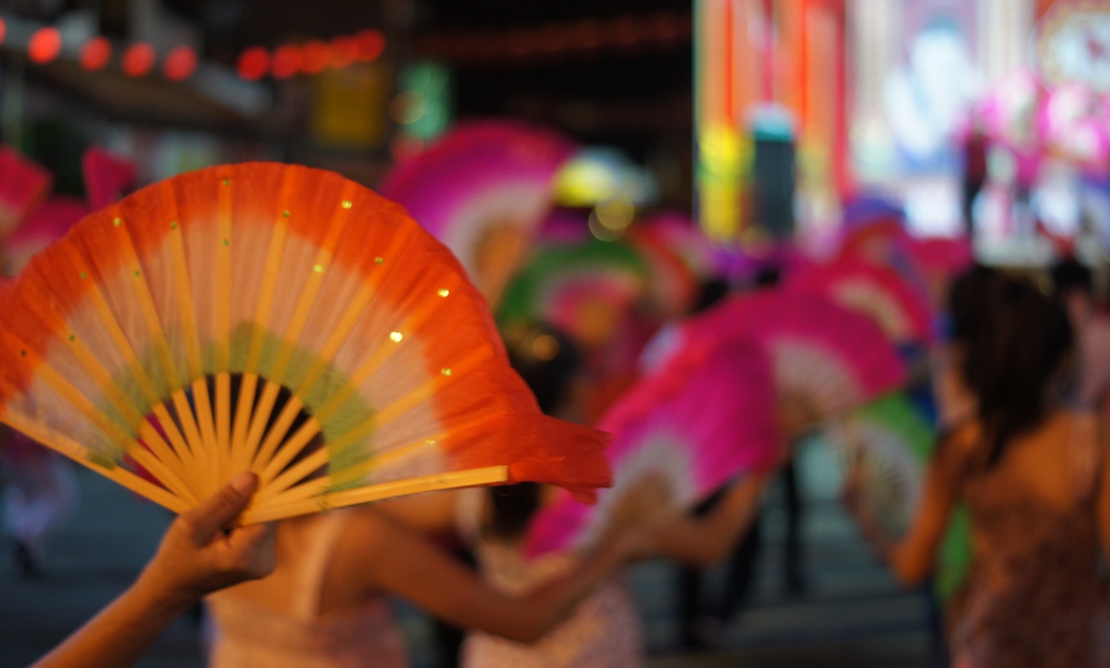 This is a close-up perspective shot of a fan dance being performed by a group of Chinese dancers on Jonker Street in Malaysia