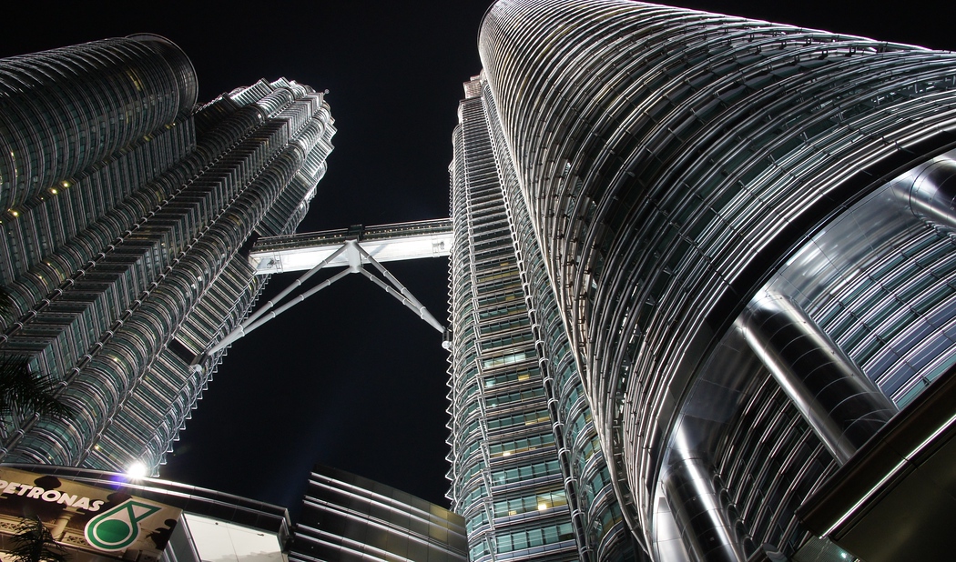 This photo is skewered towards the one tower of the Petronas Towers at night in Kuala Lumpur, Malaysia.