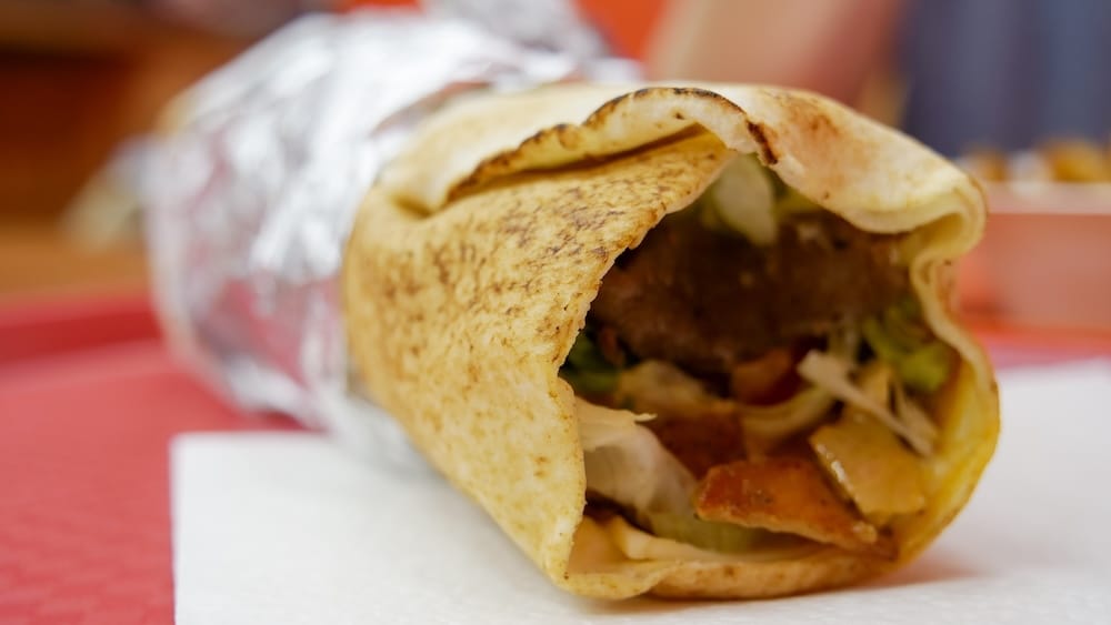 Donair mixto envuelto en aluminio, Top Donair, Jasper Avenue, Centro de Edmonton, Alberta, Canadá Vista lateral de un donair mixto de carne y pollo envuelto en papel aluminio de Top Donair en Jasper Avenue, en el centro de Edmonton, Alberta, Canadá, que muestra el exterior del pan pita tostado y la carne, lechuga y tomate en el interior.