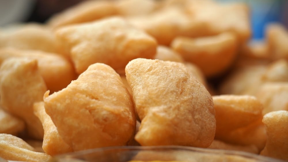 Close-up of golden Kyrgyz boorsoq, small pieces of fried dough with crisp, puffed exteriors traditionally served at tea tables, family meals, celebrations and yurt stays across Kyrgyzstan.
