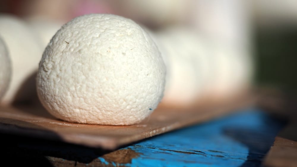 Close-up of a round white kurut ball, a traditional Kyrgyz snack made by drying salted fermented dairy curds for long-term storage and easy transport during rural and nomadic life in Kyrgyzstan.
