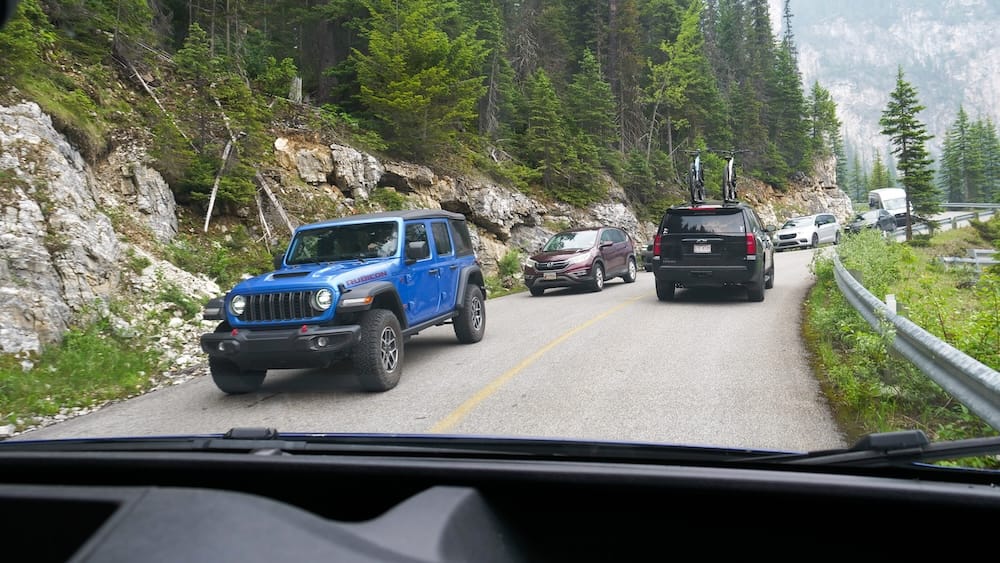 Traffic on Moraine Lake Road, Banff National Park, Alberta A line of vehicles queues along the narrow, forested Moraine Lake Road in Banff National Park, seen from inside a car, Alberta, Canada.